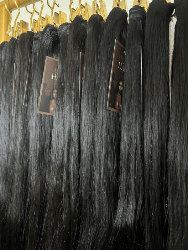 Straight Indian hair bundles in varying lengths displayed on a hair rack, showcasing the smooth, sleek texture and natural shine.