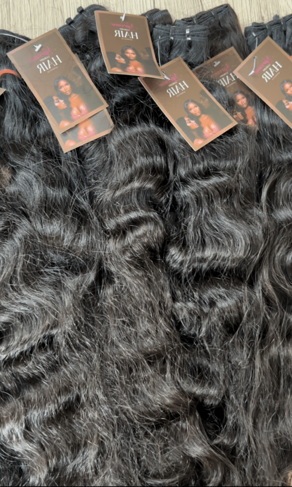 Curly raw Indian hair laid on a flat surface, displaying the tight curls, natural texture, and rich volume of the hair.