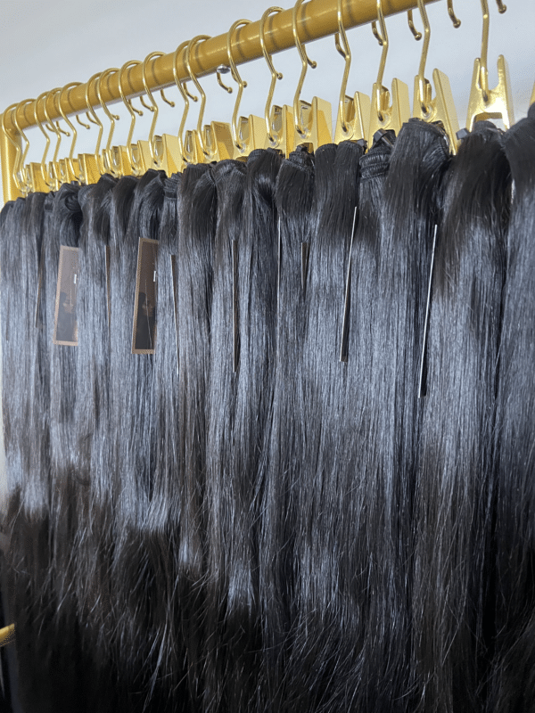 Straight Indian hair bundles in varying lengths displayed on a hair rack, showcasing the smooth, sleek texture and natural shine.